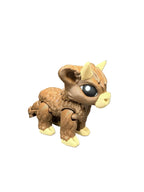 Toy figure of a Highland Cow with large eyes and horns on a gray surface.