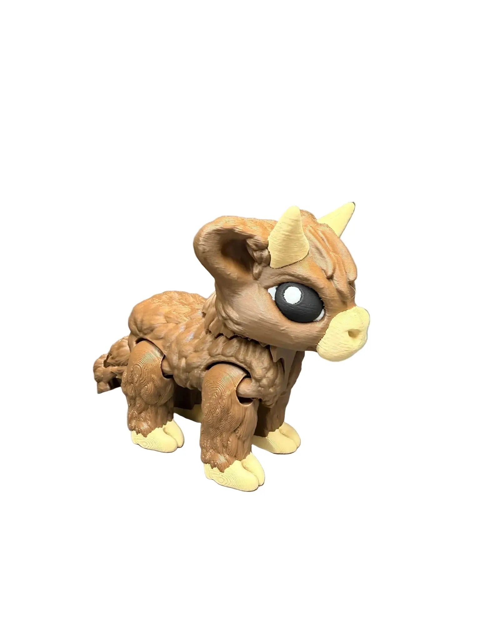 Toy figure of a Highland Cow with large eyes and horns on a gray surface.